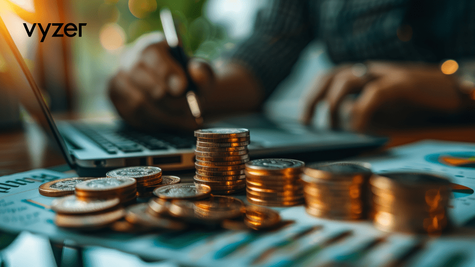 Coins stacked on financial documents with a person using a laptop, representing income-generating investment strategies